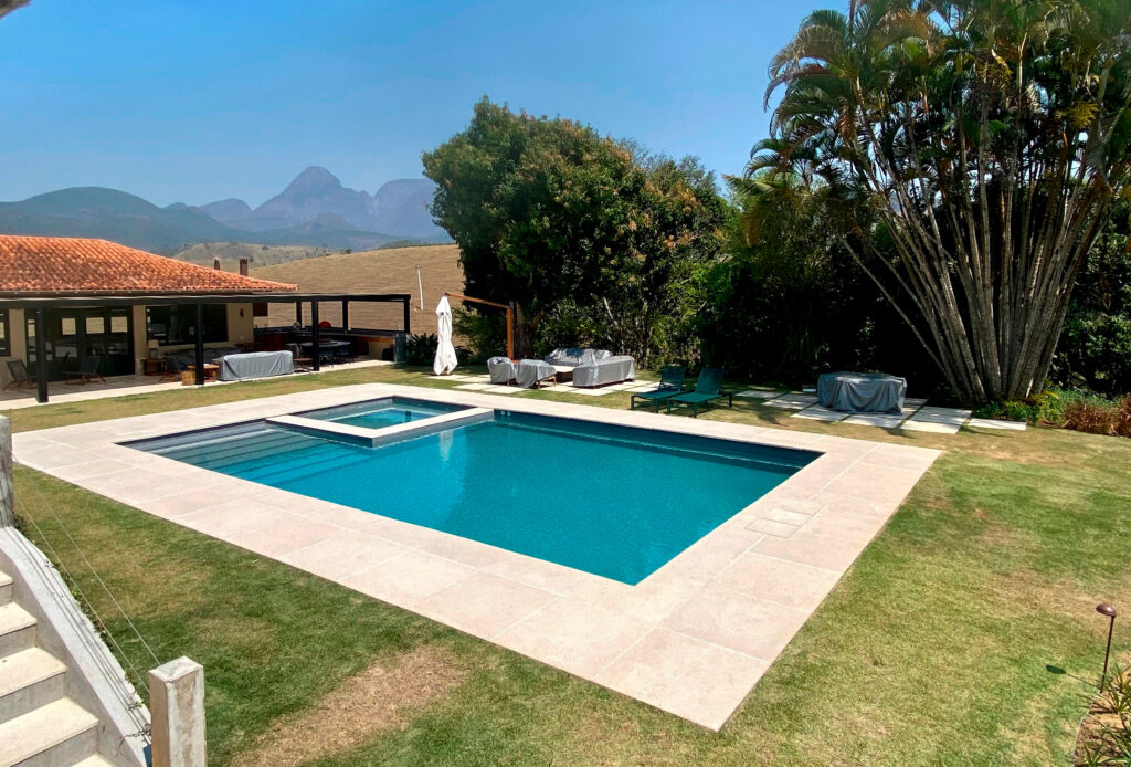 Uma piscina localizada na região serrana do Rio de Janeiro, a piscina possui hidromassagem integrada cercada de uma paisagem de montanhas - reforma-de-piscina-regiao-serrana-rj