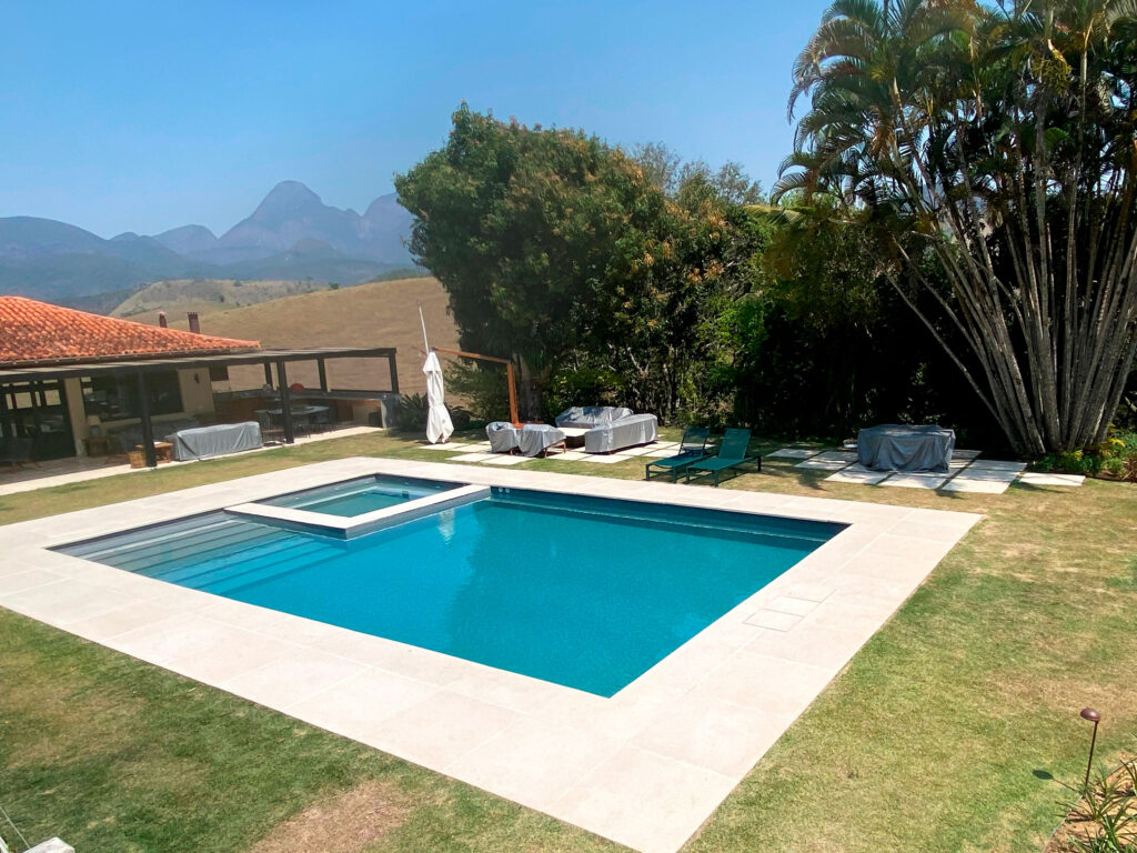 Uma piscina localizada na região serrana do Rio de Janeiro, a piscina possui hidromassagem integrada cercada de uma paisagem de montanhas - reforma-de-piscina-regiao-serrana-rj
