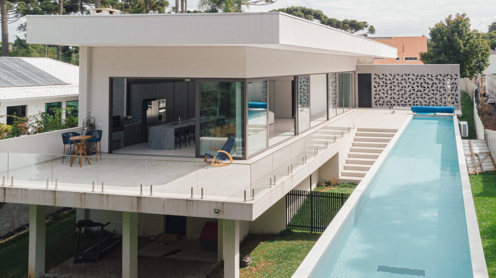 Uma piscina com raia na área externa de uma casa grande e moderna - projeto-de-piscina-raia-curitiba