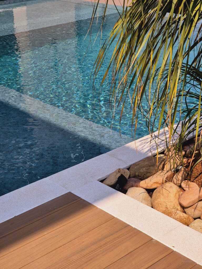 Uma piscina em formato de L com borda infinita em um quintal de uma casa - projeto-piscina-em-l-com-prainha-e-borda-infinita-curitiba