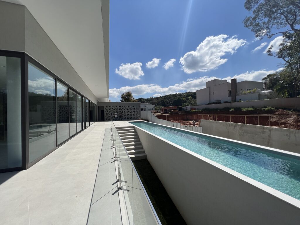 Uma piscina com raia na área externa de uma casa grande e moderna - projeto-de-piscina-raia-curitiba