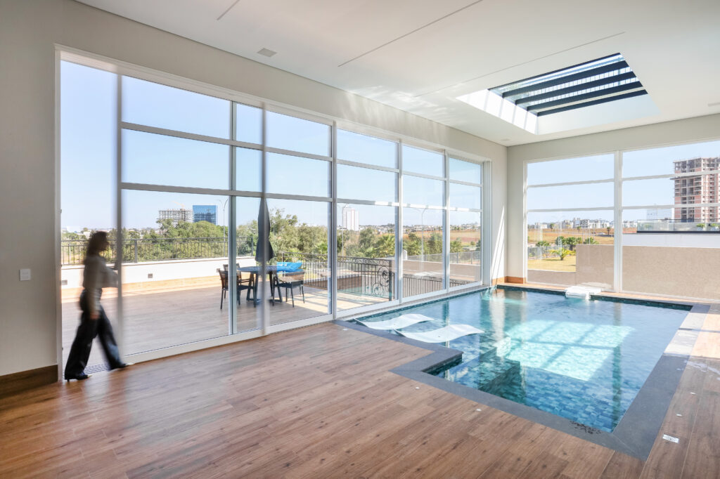 Uma piscina localizada no ambiente interno da casa, o espaço possui janelas grandes e uma vista para a piscina - projeto-de-piscina-interna